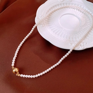 Detailed view of vintage pearl necklace with gold clasp on brown velvet and porcelain plate