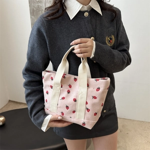 Pink corduroy tote bag with strawberry prints and cream fabric handles on model