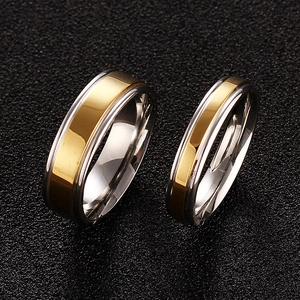 Polished silver and gold titanium steel couple rings set on a dark textured background