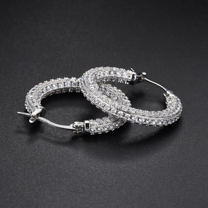 Macro shot of silver paved rhinestone hoop earrings on a black background