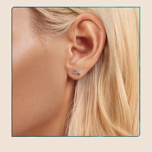Macro shot of silver infinity stud earrings with sparkling stones on model