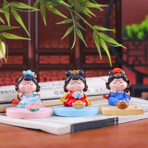 Three traditional Chinese dolls on a vintage book with screen and bamboo leaves