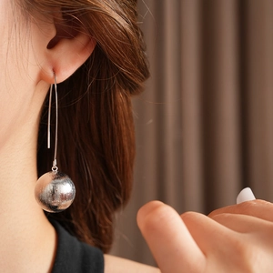 Gros plan d'élégantes boucles d'oreilles boules argentées portées par un mannequin