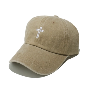 Close-up of white Jesus cross embroidery on a vintage washed khaki baseball cap
