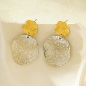 Gros plan de boucles d'oreilles bicolores avec pendentifs texturés en or et argent