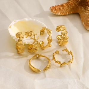 Detailed set of gold starfish and seashell rings displayed on a beach-themed background