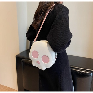 Detail view of round white skull crossbody bag with pink accents and long leather strap
