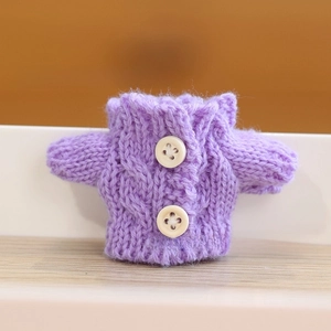 Detail of purple cable-knit doll sweater featuring white round buttons and rich textures