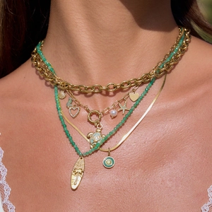 Close-up of layered gold chain and green beaded necklace with ocean themed charms