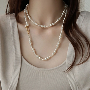 Détail d'un élégant collier de perles à deux rangs avec un fermoir doré en fer à cheval