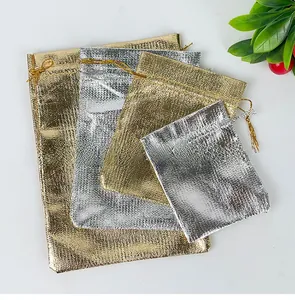 Close-up of metallic gold and silver drawstring gift bags with woven texture and cords