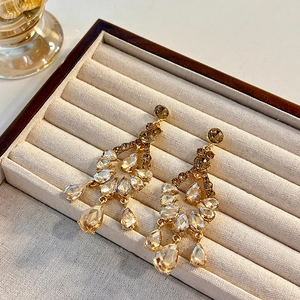 Boucles d'oreilles pampilles dorées avec strass brillants dans un coffret à bijoux de luxe