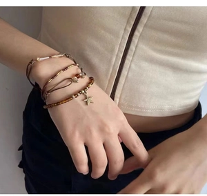 Détail d'un ensemble de bracelets bohèmes à perles avec breloque étoile dorée au poignet