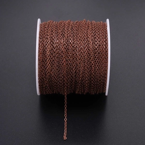 Close-up of bronze metal plating cross chain on white plastic spool for DIY jewelry
