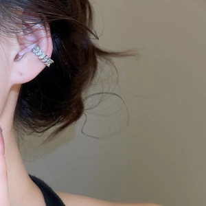 Macro detail of elegant silver zircon bow ear cuff worn on a female model with soft lighting