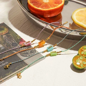 Detailed close-up of colorful braided LOVE letter bracelets with vibrant summer fruit props