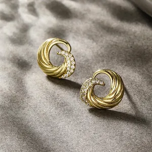 Macro detail of gold-plated spiral stud earrings with pave-set shimmering zircon stones