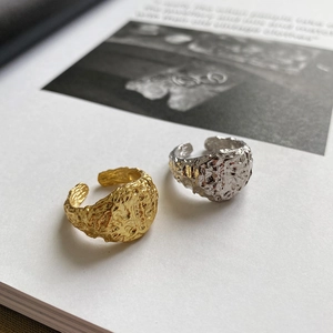 Detail of minimalist S925 silver rings with irregular hammered lava texture on book