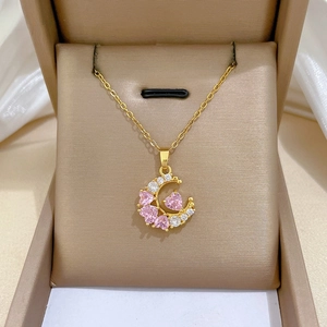 Detailed shot of crescent moon necklace with pink heart zircons in 18K gold finish
