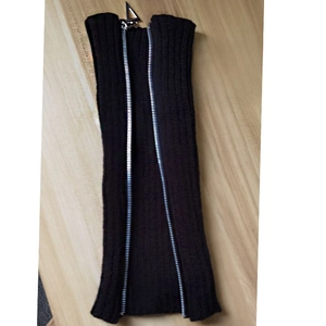 Detail of black ribbed knit leg warmer featuring a fully functional silver metal zipper