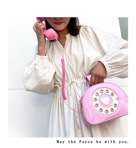 Close-up of pink vintage telephone bag with dial detail and heart center on white dress
