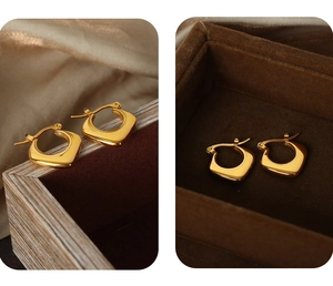 Details von goldenen U-förmigen geometrischen Ohrringen auf Seide und Samt-Schmuckbox