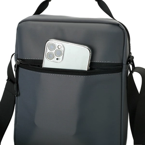 Detail of dark grey waterproof crossbody bag with smartphone in front zipper pocket
