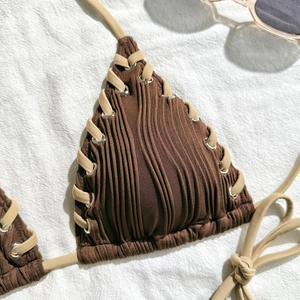Detail of dark brown ribbed bikini top featuring silver eyelets and criss-cross ties