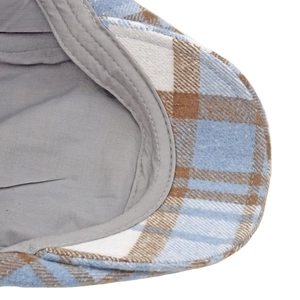 Macro detail of plaid wool newsboy cap showing blue-brown fabric and stitching
