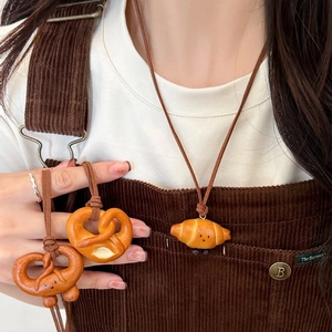 Simpatica collana con ciondolo a croissant e pretzel realistico con faccina sorridente