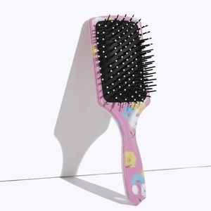 Detail of pink floral air cushion comb featuring black bristles with white massage tips