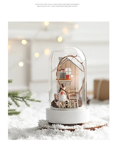 Détail d'un dôme en verre nordique avec figurines de Noël miniatures et scène de forêt enneigée