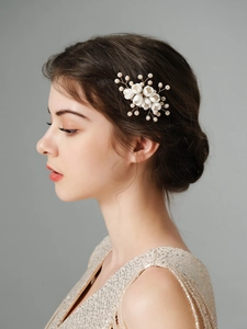 Detailed close-up of handmade white ceramic floral hair comb with pearl accents on gold wire