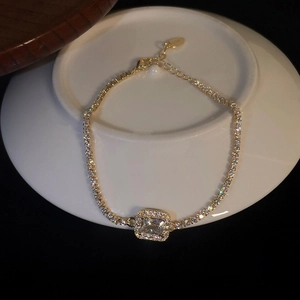 Elegant gold square zircon tennis bracelet on white ceramic base with black background