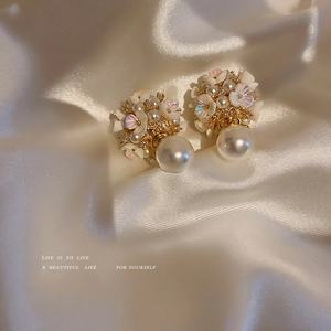 Boucles d'oreilles fleurs et perles avec zircons sur fond de soie blanche douce