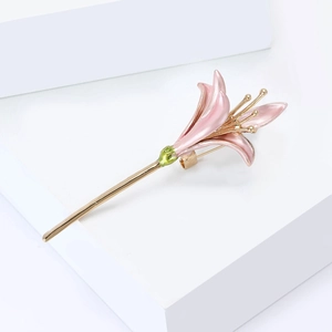 Macro detail of a pink enamel lily flower brooch with elegant gold-plated metal accents