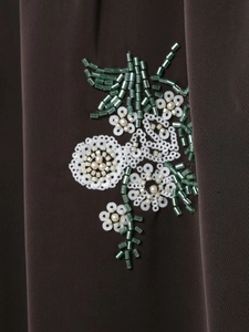 Vue macro détaillée de la broderie florale en paillettes vertes sur tissu marron