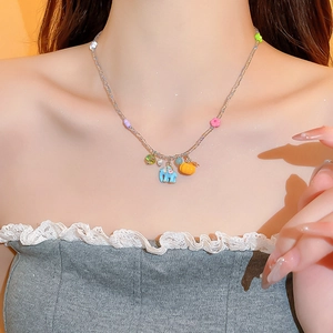 Detail of necklace with blue elephant, orange pumpkin pendants and clear beads on model