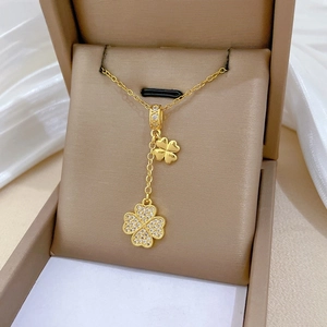 Detail of gold clover necklace with one polished and one pavé-set zirconia pendant