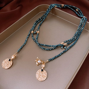Close-up of vintage layered beads, golden bee pendant with pearl and antique coin charms