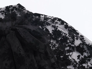 Detail of elegant black mesh neckline with flocking floral pattern and ribbon tie bow