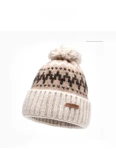 Detail of beige knit beanie showing wave jacquard pattern and brown leather label