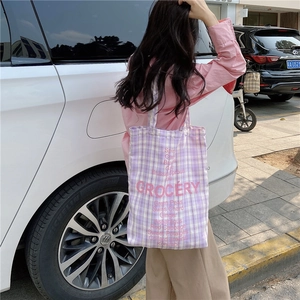 Street view of purple checkered canvas grocery bag with pink lettering shown on model