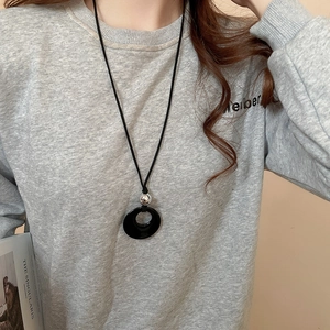 Detail einer ethnischen Halskette mit schwarzem Ringanhänger und silberner Perle am Model