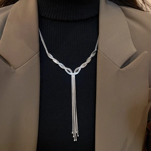 Detail of silver layered tassel necklace with delicate intertwined chains on a black top