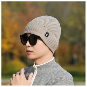 Detail of light beige knitted beanie showing fine ribbed texture and square logo patch