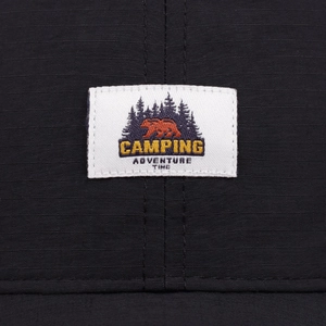 Detailed macro view of black quick-dry baseball cap with camping adventure woven patch