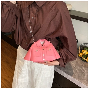 Detail of pink jacket-shaped creative crossbody bag with silver chain strap on model