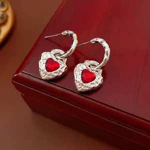 Silver heart earrings with red gemstone on a luxury wooden jewelry box display