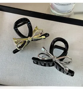 Detail of metal bow hair clips in gold and silver finish with black resin shark clip